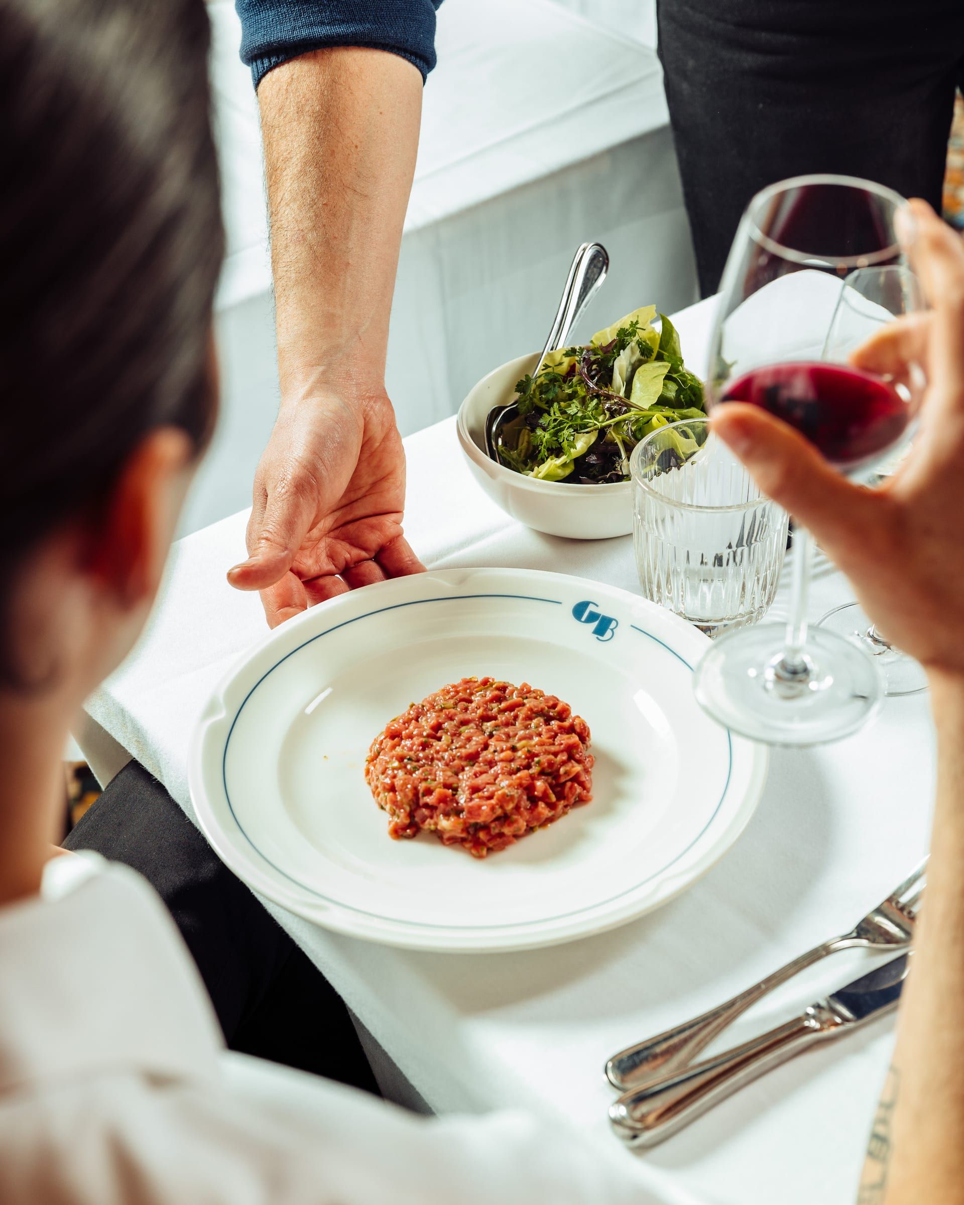 Tartare de bœuf servi à table, salade et verre de vin rouge